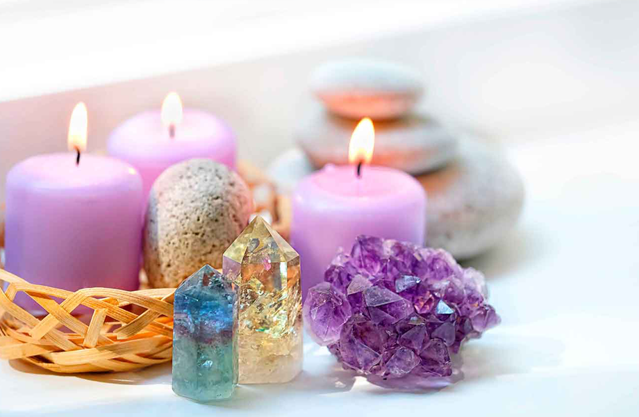 Velas encendidas junto a cristales y piedras decorativas sobre una superficie blanca en un ambiente de relajación.